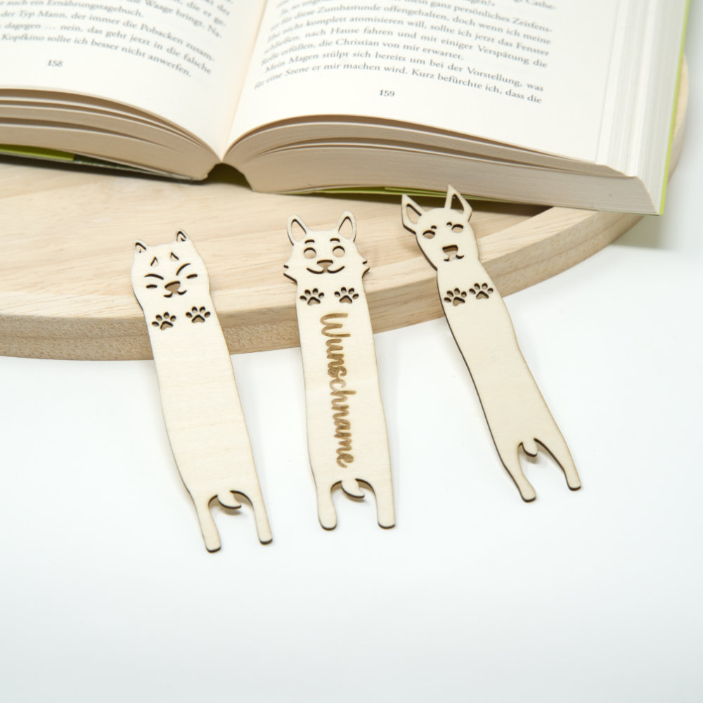 3 Holz Lesezeichen in Hunde Motiv liegen neben einem offenen Buch